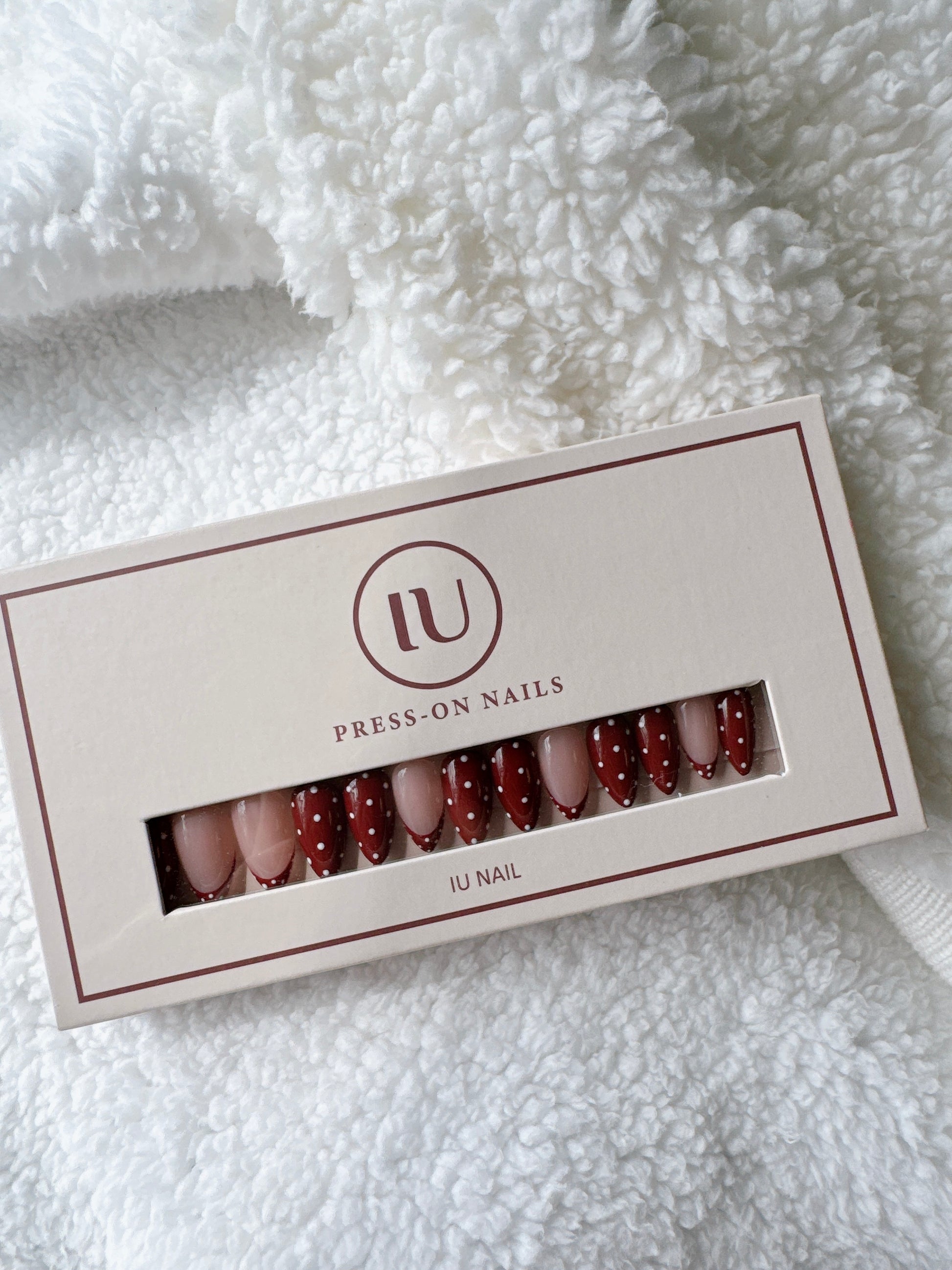 Press-on nails set with red and nude tones, polka dot design in a box on soft white fabric