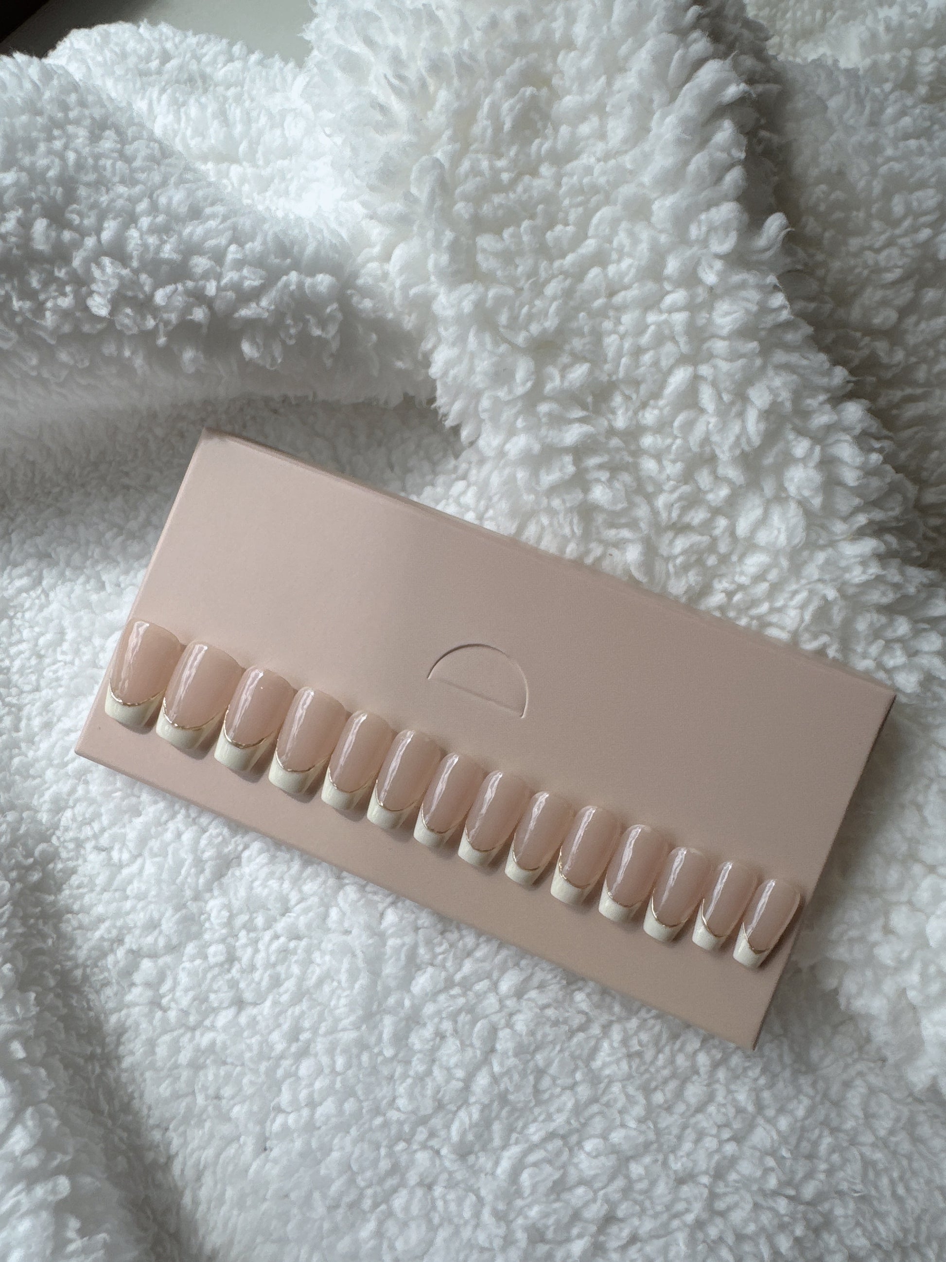 French tip press-on nails set displayed on a beige card over a white textured fabric