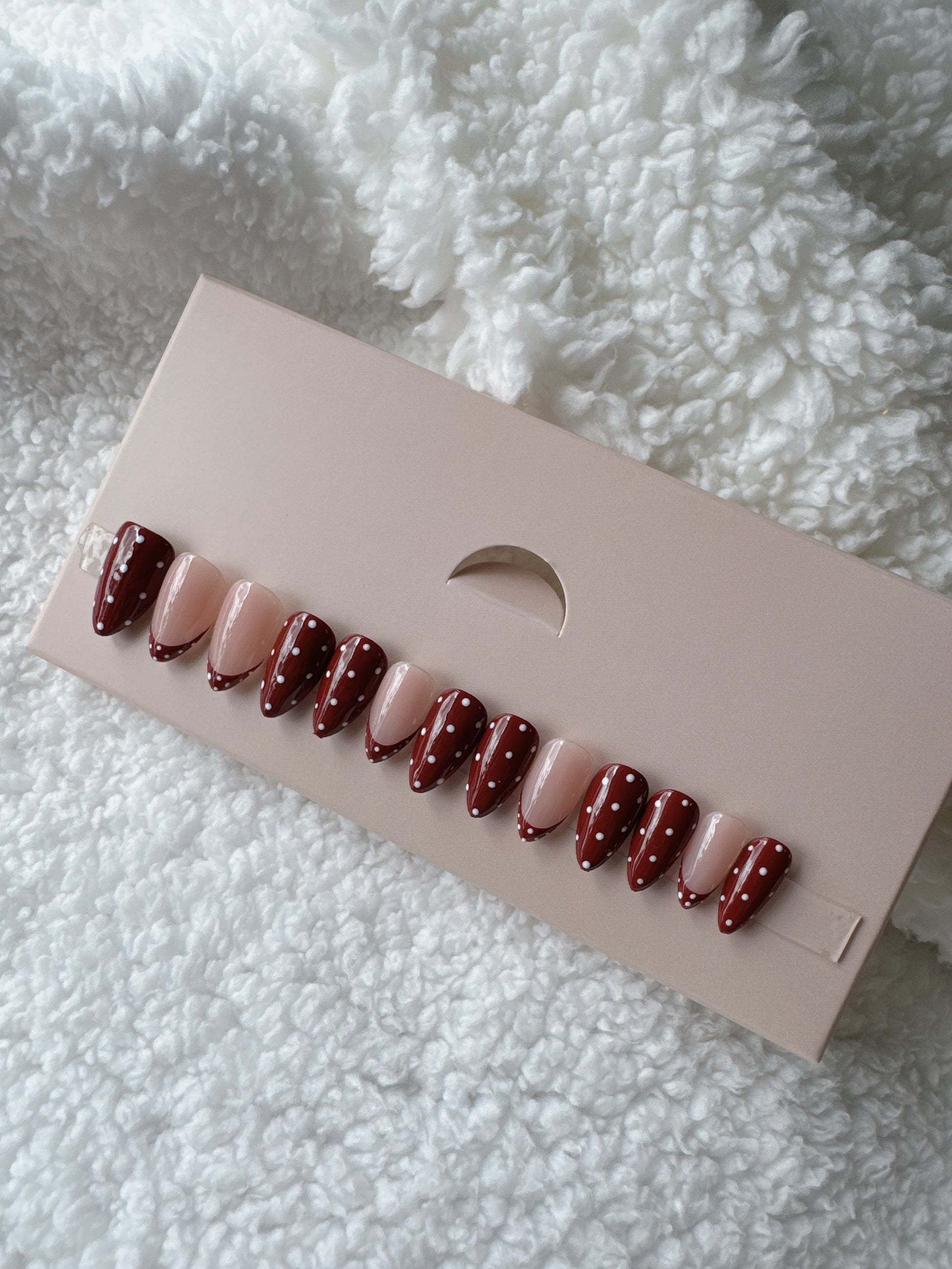 Almond-shaped press on nails with burgundy and nude colors, polka dot nail art design