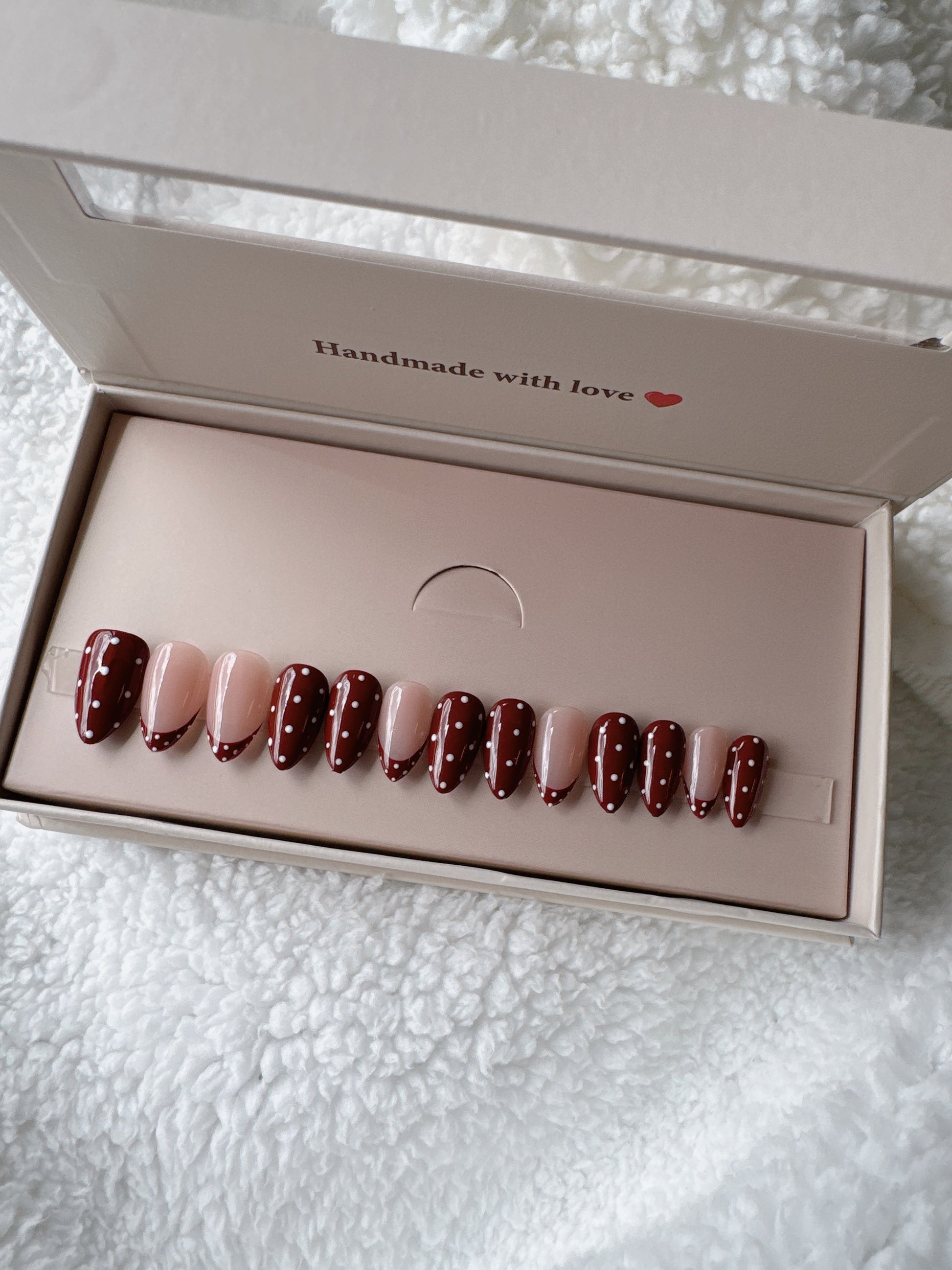 Red and nude polka dot press on nails in a gift box on white textured fabric