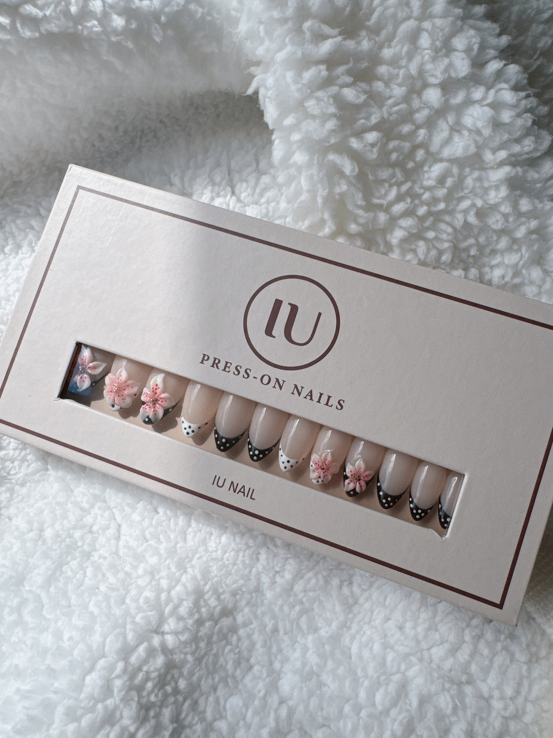Box of nude press-on nails with black and white polka dot tips and pink 3D floral accents