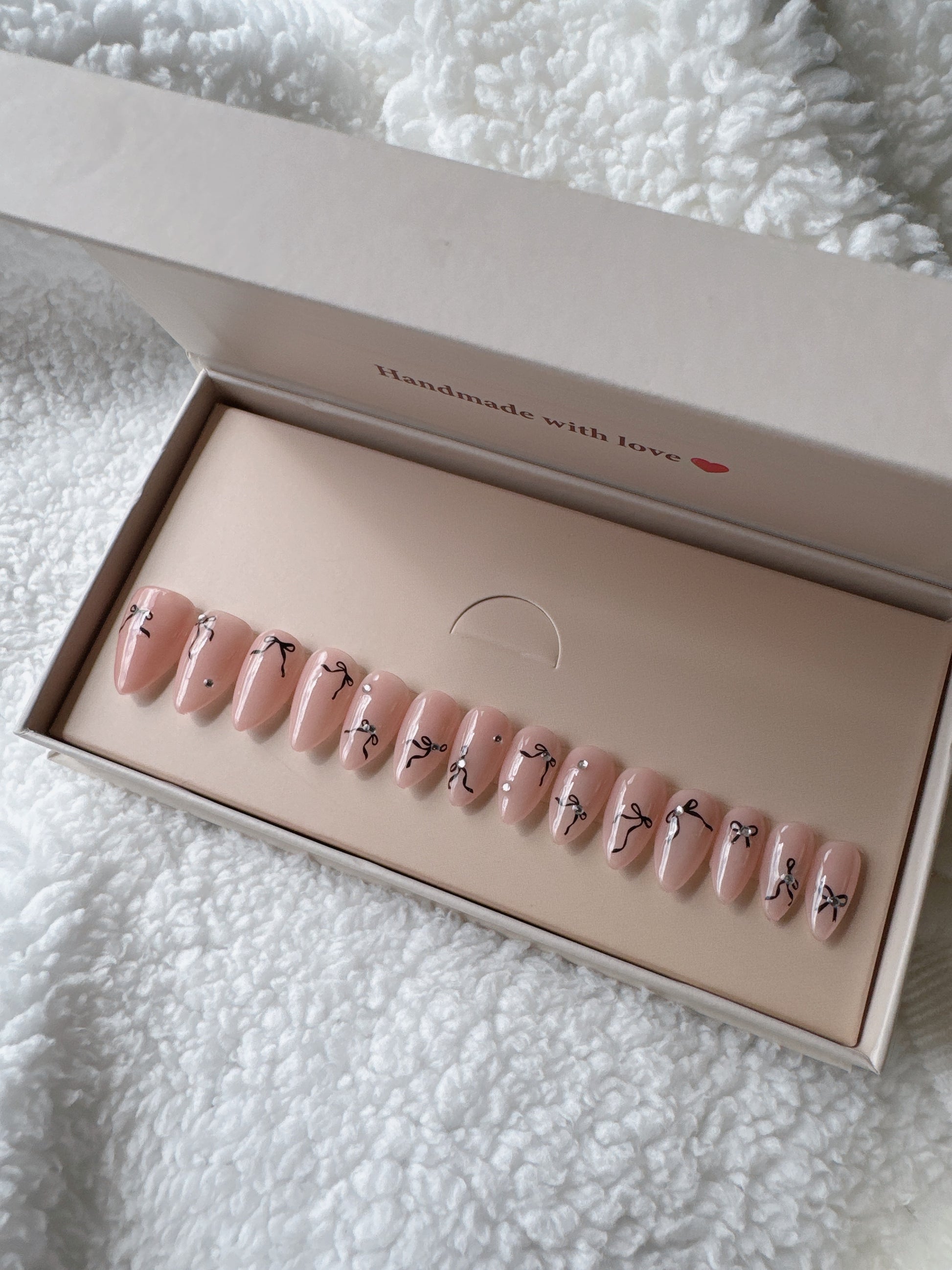 Handmade almond press on nails with nude base and black bow nail art in gift box